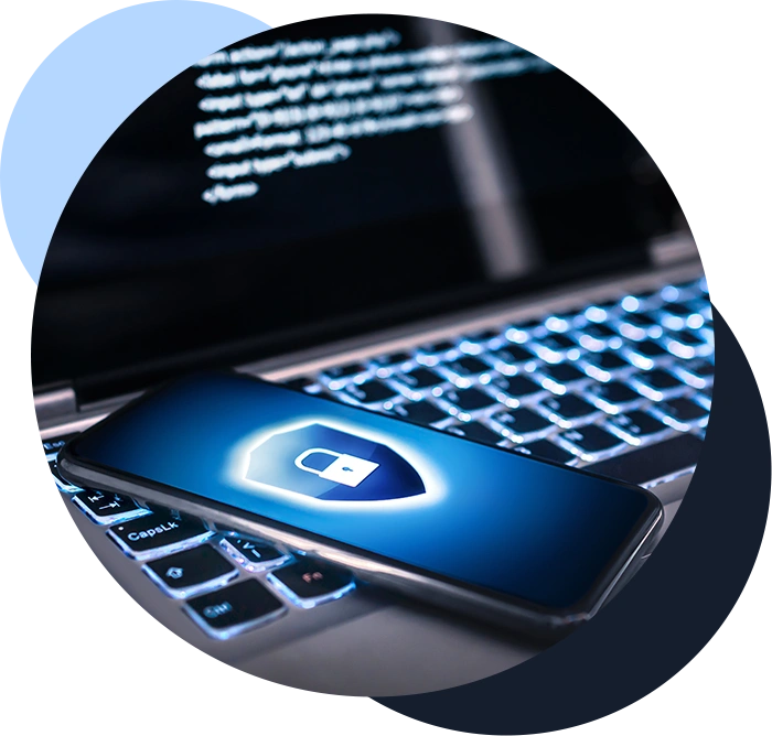 Color image of a cell phone depicting security with a lock and shield icon on it, sitting on a laptop