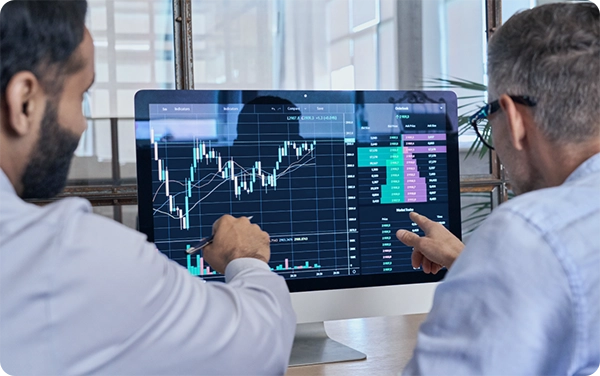 Two office workers reviewing analytics together on a desktop computer