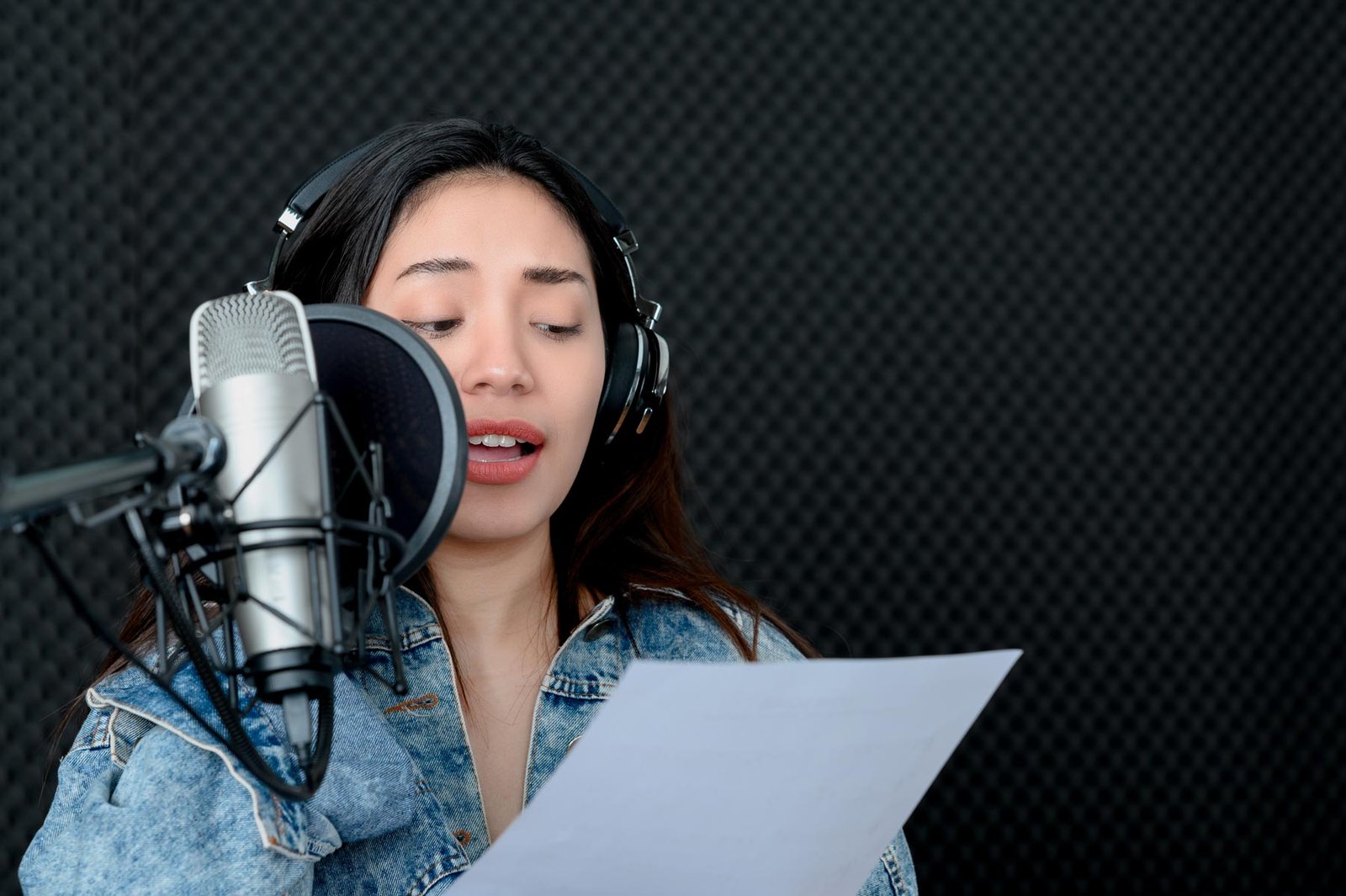 Woman performing voiceover work in a studio sound booth
